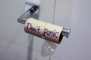 Leere Klopapierrolle auf Metallhalter mit Aufschrift "Don't panic"